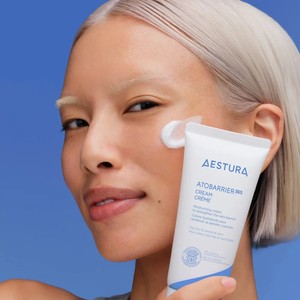 Woman holding an AESTURA ATOBARRIER365 Cream tube to her cheek