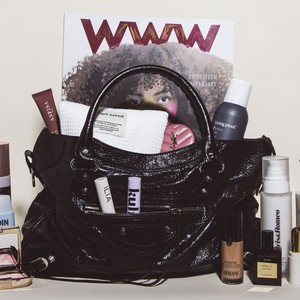 Black Balenciaga City Bag filled with beauty products and a Who What Wear magazine