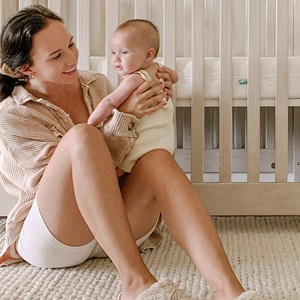 Mom holding her baby beside a crib, from the Newton Baby Fall Favorites Giveaway page