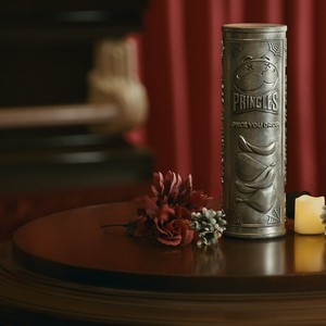 Pringles Once You Drop can-shaped urn on a wooden table with candles