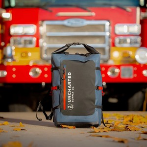 Uncharted Supply Co. Seventy2 Pro Survival System backpack in front of a fire truck