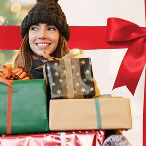 Smiling woman in a winter hat carrying wrapped holiday gifts from the Valpak Holiday Haul promo